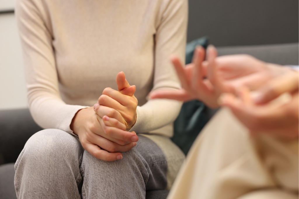 Hands clasped during a supportive psychological therapy session