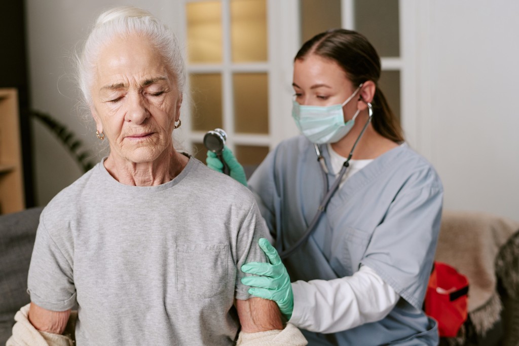 Clinician listening to an older patient’s lungs with a stethoscope