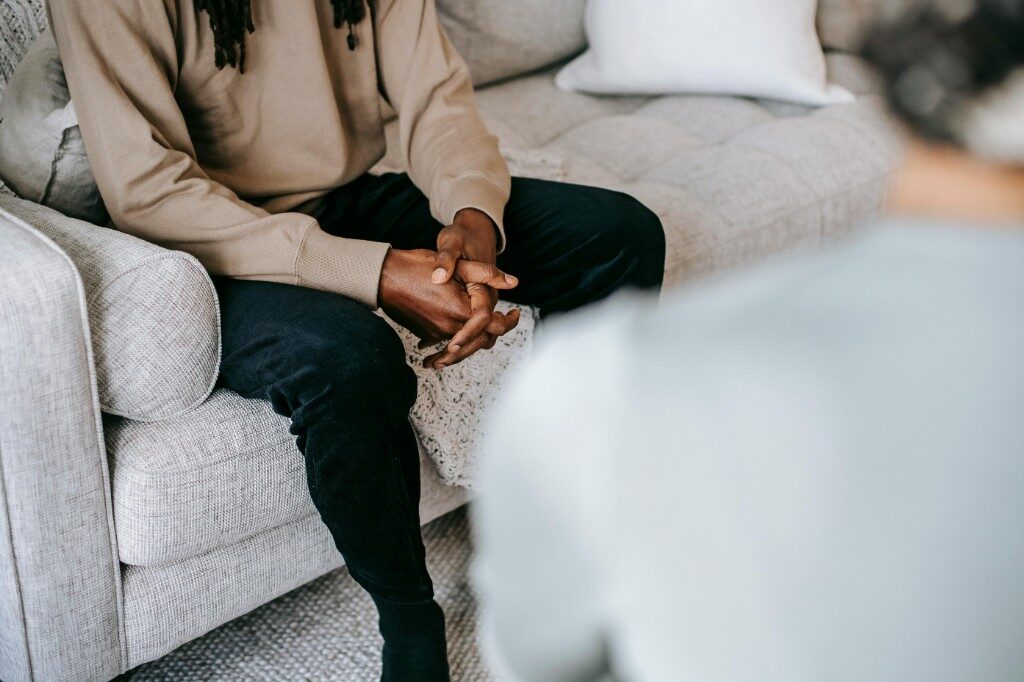 Person seated on a sofa during a one-on-one counselling conversation