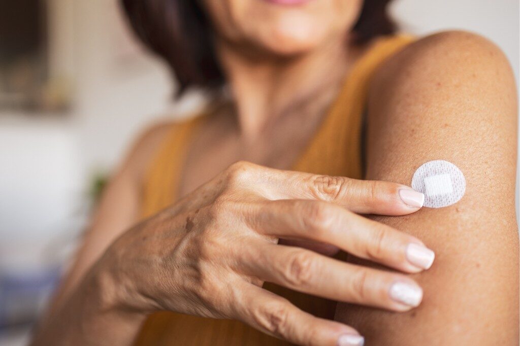 Person applying a nicotine replacement patch to their upper arm