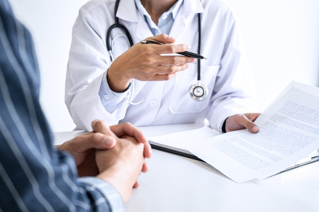 Doctor in a white coat reviewing a document with a patient during a consultation