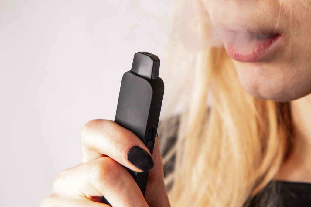 Close-up of a person holding a black vaping device